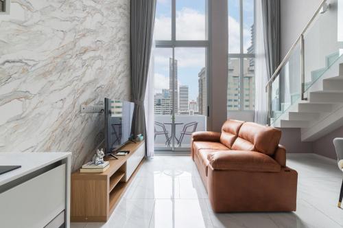 a living room with a leather chair and a television at The Echelon Sukhumvit 11 by LeFoyer in Bangkok