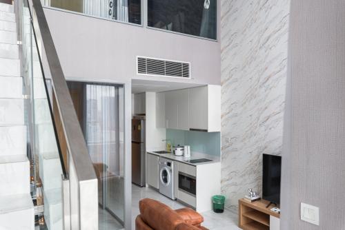 a living room with a couch and a television in a house at The Echelon Sukhumvit 11 by LeFoyer in Bangkok