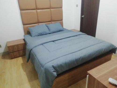 a bedroom with a bed with blue sheets and a headboard at Apartemen Transpark Cibubur by Royal Home in Depok
