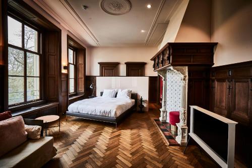 a bedroom with a bed and a couch and a tv at Parc Broekhuizen l Culinair landgoed in Leersum