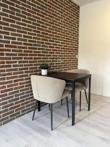 a black table and a chair and a brick wall at Mooi appartement in centrum dorp in Nieuwleusen