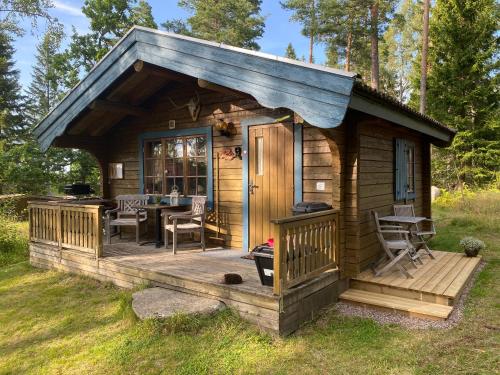a cabin with a deck with a table at Timrad stuga i kanten av skogen med SPA möjlighet in Mullsjö