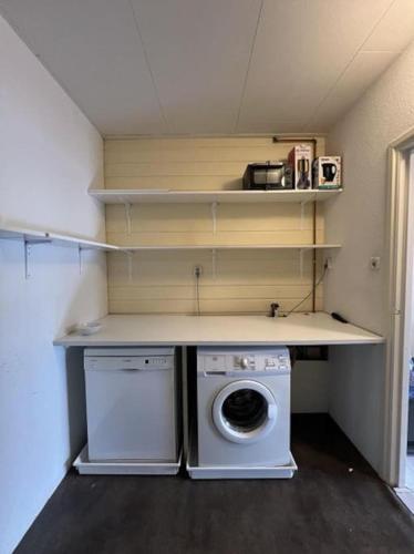 a laundry room with a washing machine and shelves at Mooi appartement in centrum dorp in Nieuwleusen
