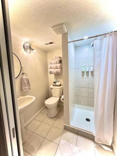 a bathroom with a shower and a toilet and a sink at Cedar Street Retreat - Heart of Aksarben! in Omaha