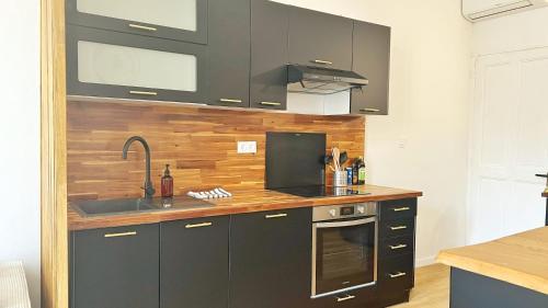 a kitchen with black cabinets and a sink at Grand Cosy Family Stay - Centre historique Avignon in Avignon