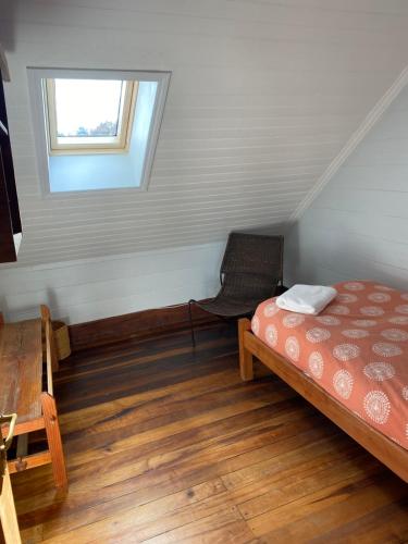 a small room with a bed and a window at Hostal Compass del Sur in Puerto Varas