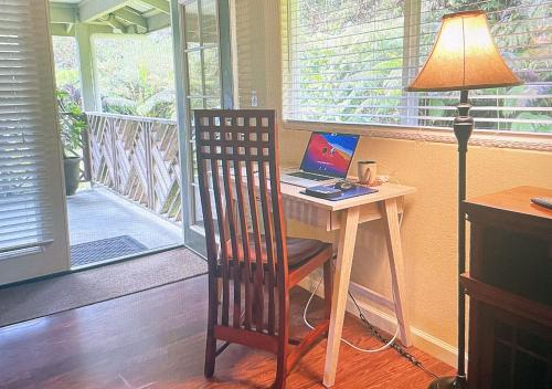 a desk with a laptop computer on it with a lamp at 5th Street Ohana in Volcano