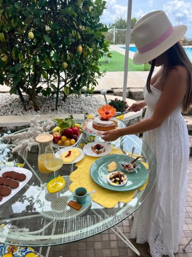 a woman in a hat standing at a table with food at La Canostra Capri - luxury ROOM ad Anacapri in Anacapri