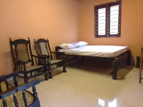a room with a bed and two chairs and a window at Kit Cott Resort and Retreat in Teligama