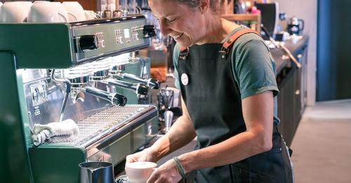 a woman in a kitchen preparing a drink at Story Thusis in Thusis