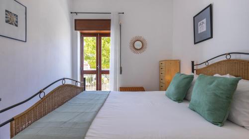 a bedroom with a large white bed with green pillows at Seaside Getaway With Balcony by LovelyStay in Almada