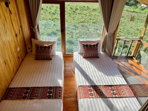 two beds in a room with a large window at Muong Tra Stream Homestay in Làng Cac