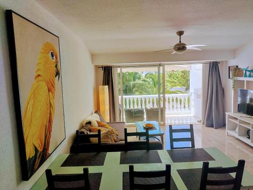 Una sala de estar con una mesa de comedor con un cuadro de loro. en Apartment Residencia Carabela, en Costa del Silencio