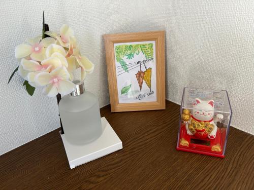 a table with a vase with flowers and a picture at 120平米 5BR House, Near Ueno and Asakusa, Parking 2间浴室5室1厅 FlowerTea Hotel in Tokyo