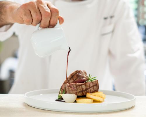 a chef is pouring sauce on a plate of food at Relais CastelBigozzi in Monteriggioni