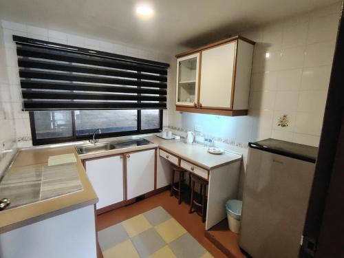 a small kitchen with a sink and a refrigerator at Highland Hideaway 1 Bedroom Apartment at Equatorial Hill Resort in Brinchang