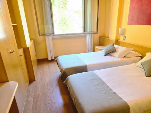 two beds in a room with a window at Mokinba Hotels Sant'Ambroeus in Milan