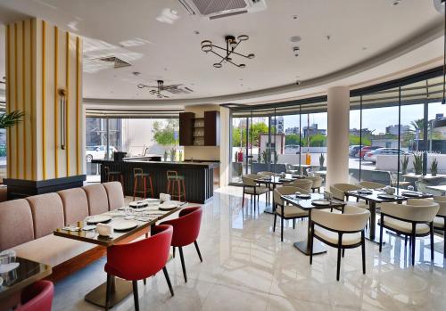 a restaurant with tables and chairs and windows at Caddem Inn Hotel in Mağusa