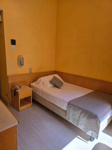 a small bedroom with two beds and a night stand at Mokinba Hotels Sant'Ambroeus in Milan