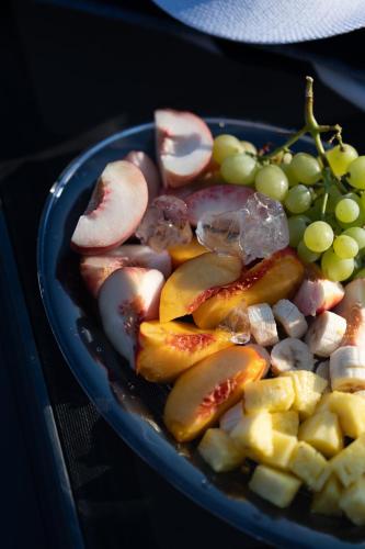a blue bowl of fruit with apples and grapes at Villa & Stone House with Pool, 10 Mins to Skala Eressos Beach in Eresos