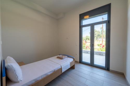 a bedroom with a bed and a large window at Villa & Stone House with Pool, 10 Mins to Skala Eressos Beach in Eresos