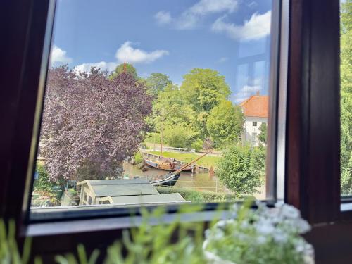 a view of a river from a window with flowers at FeWo Kajüte 10 - Carolinensiel in Carolinensiel