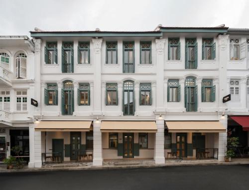 a white building with tables in front of it at Claude Hotel in Singapore