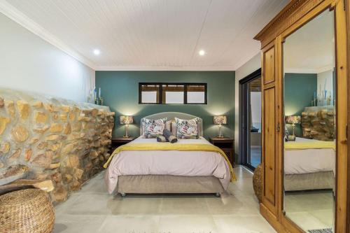 a bedroom with a large bed and a stone wall at Heuwels in Blauwvlei
