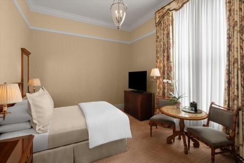 a hotel room with a bed and a table and a television at Capital Hotel in Little Rock