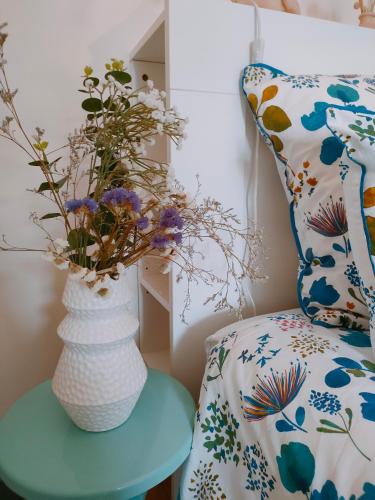 eine Vase mit Blumen auf einem Tisch neben einem Stuhl in der Unterkunft La Suite 27 bis, appartement indépendant avec terrasse, proche gare et centre in Guingamp