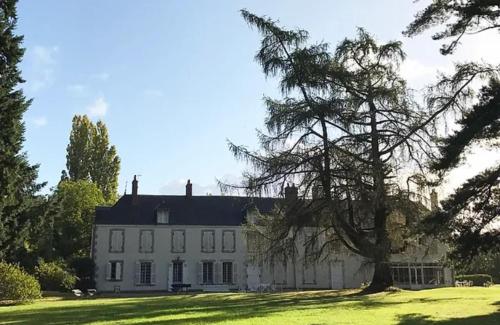 a large white house with a tree in front of it at Domaine Les Bruyères in Autry-le-Châtel