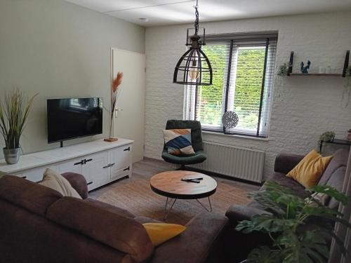 a living room with a couch and a tv at Vakantiehuis vlakbij Duitse grens in Beek