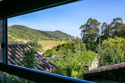 a view of a hill from a window at Moradas do Vale Praia do Rosa in Praia do Rosa