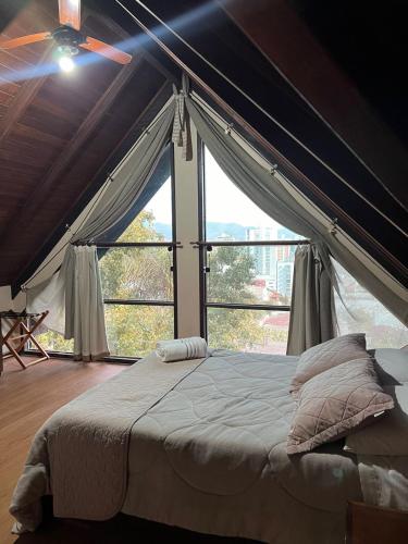 a bedroom with a canopy bed with a large window at Pousada Casa da Pedra in Blumenau