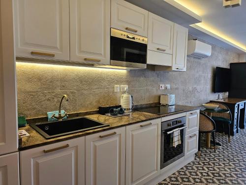a kitchen with white cabinets and a sink at Balcony Hotel in St Julian's
