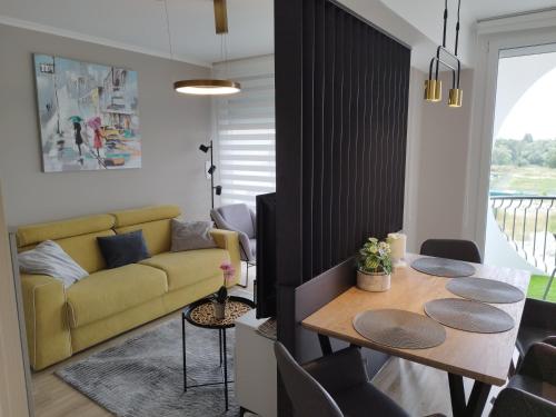 sala de estar con mesa y sofá amarillo en Silver Harmony Apartman Siófok, en Siófok