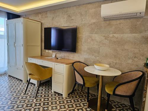 a room with a table and a tv on a wall at Balcony Hotel in St Julian's