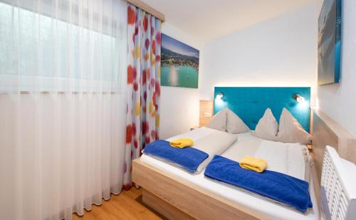a bedroom with a bed with blue and white sheets at Barry Memle Directly at the Lake in Velden am Wörthersee