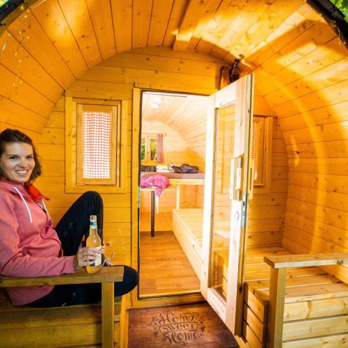 a woman sitting in the inside of a wooden cabin at Fasshotel Westernwagen, beheizt 2-3 Personen in Kirchensittenbach