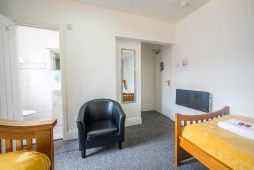 a bedroom with a bed and a chair and a television at Driftwood Rooms in Blackpool