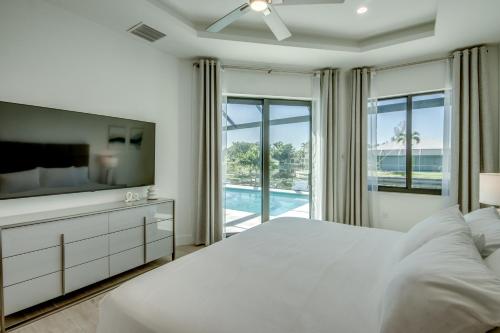 a bedroom with a white bed and a television at BRANDNEW Villa-PureSun at Canal intersection, heated saltwater pool and spa, facing south in Cape Coral