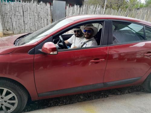 two men are sitting in a red car at Hostal Makesa Tatacoa in Villavieja