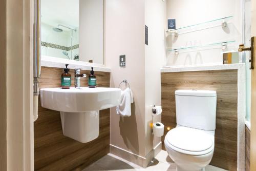 a bathroom with a white toilet and a sink at voco Oxford Thames by IHG in Oxford