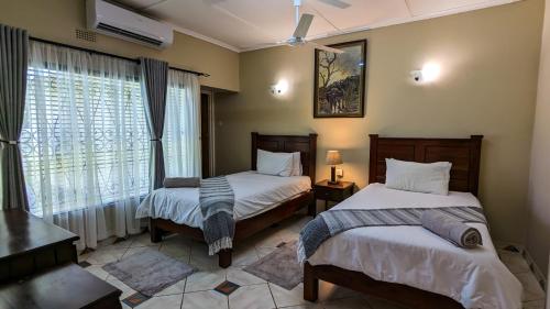 a bedroom with two beds and a window at Zambezi Family Lodge - Buffalo Room in Victoria Falls