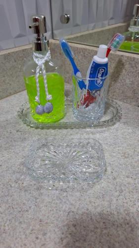a glass toothbrush holder on a counter next to a sink at Aldeia das Aguas Quartier in Barra do Piraí