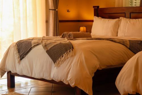 a bedroom with a large bed with white sheets at Zambezi Family Lodge - Elephant Room in Victoria Falls