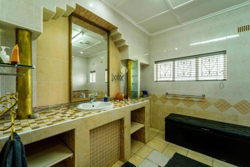 a bathroom with a sink and a large mirror at Zambezi Family Lodge - Elephant Room in Victoria Falls
