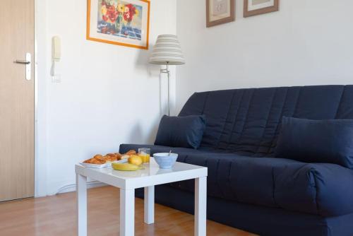 - un salon avec un canapé bleu et une table avec de la nourriture dans l'établissement Aurore - T1 21, à Carcassonne