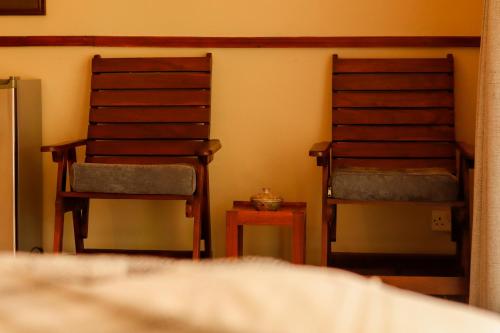 two wooden chairs sitting in a room with a table at Zambezi Family Lodge - Elephant Room in Victoria Falls