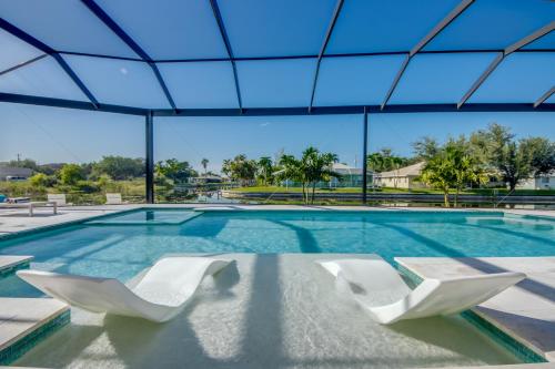 a swimming pool with two white chairs in it at BRANDNEW Villa-PureSun at Canal intersection, heated saltwater pool and spa, facing south in Cape Coral